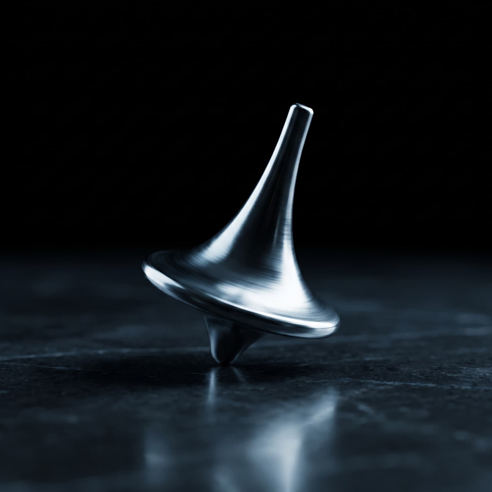 The Totem, a polished titanium spinning top, mid-spin on a dark surface